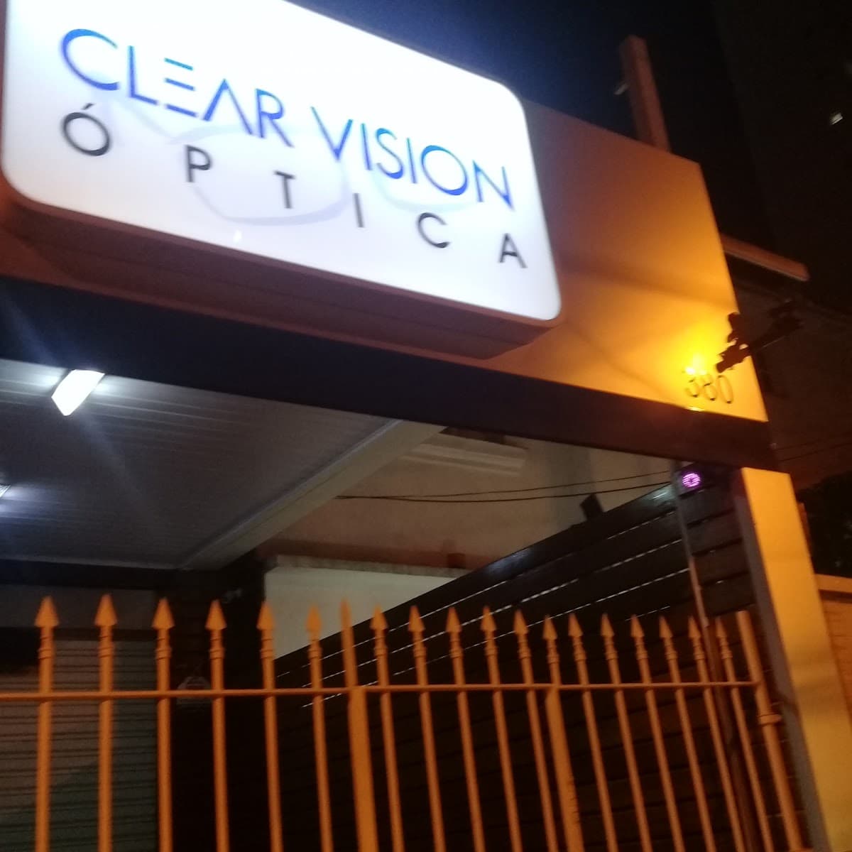 Fachada da Clear Vision Óptica à noite — letreiro luminoso CLEAR VISION ÓPTICA no número 380 da Rua Heitor Peixoto, Cambuci